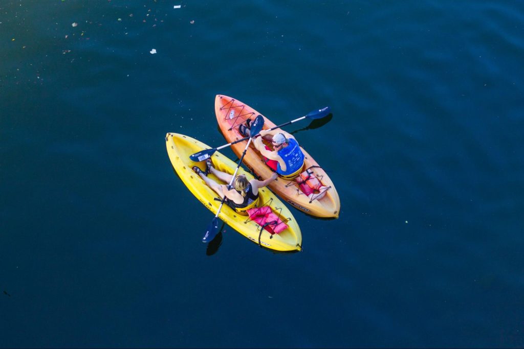 A couple kayak together on a dark blue lake. Photo: Roland Chanson