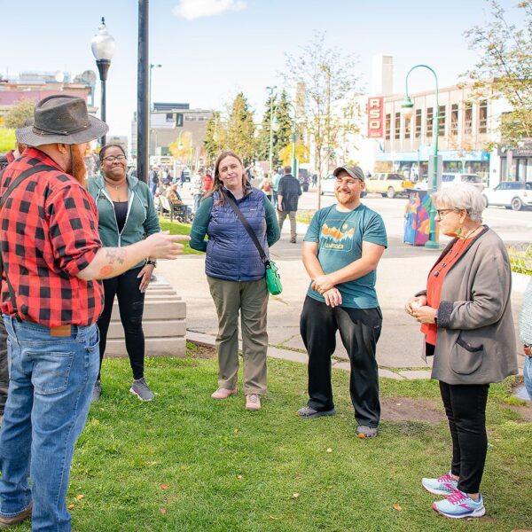 Group of people engaged in an outdoor conversation on a sunny day during Alaska Food Tours.