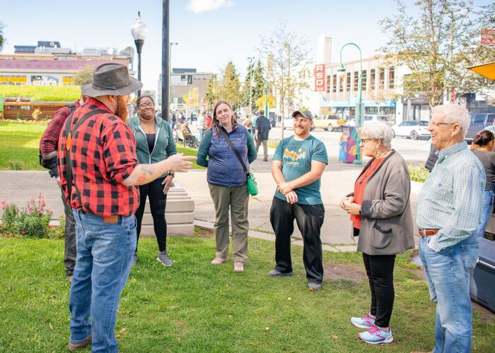 Group of people engaged in an outdoor conversation on a sunny day during Alaska Food Tours.