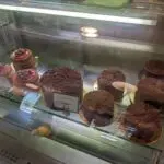 Assorted cakes displayed in a glass bakery case during guided Anchorage food tours, including berry-topped cakes and chocolate cakes with shavings.
