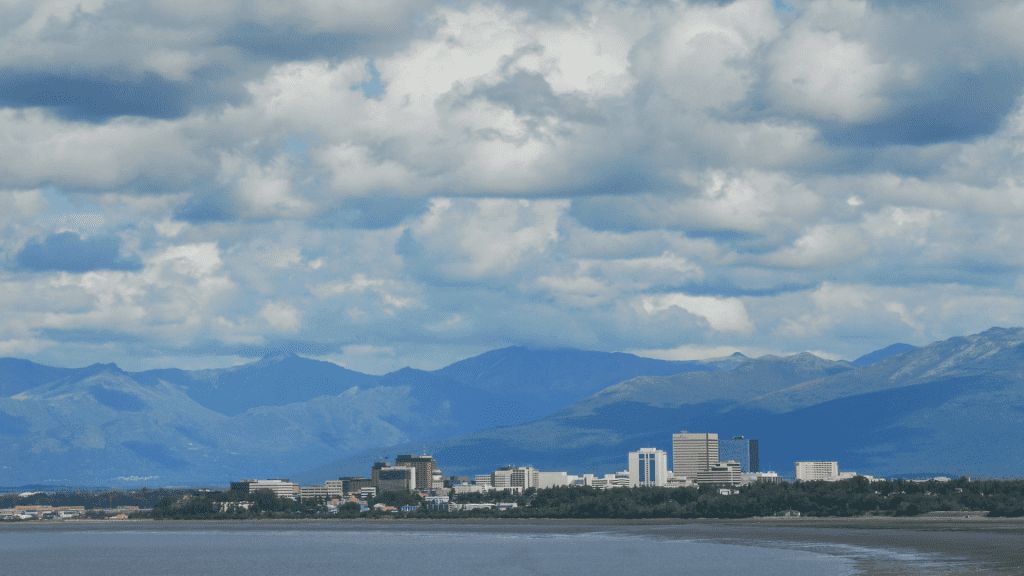 A coastal city skyline set against a backdrop of mountains and a partly cloudy sky, perfect for sightseeing.