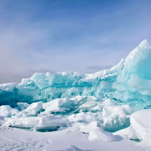 Expansive ice formations with varying shades of blue and white under a clear sky.