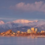 Anchorage city skyline at sunset with snow-covered mountains in the background and calm winter water in the foreground—a perfect scene for any Anchorage travel guide. Anchorage city skyline at sunset with snow-covered mountains in the background and calm winter water in the foreground—a perfect scene for any Anchorage travel guide.